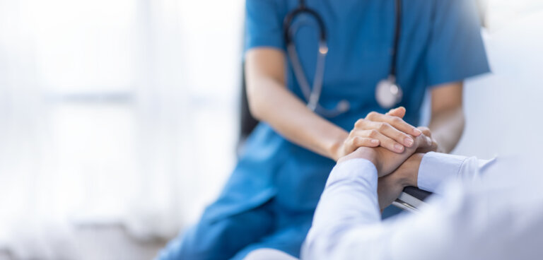 Cropped shot of a female nurse hold her senior patient's hand. Giving Support. Doctor helping old patient with Alzheimer's disease. Female carer holding hands of senior man healthcare advocacy hammes law